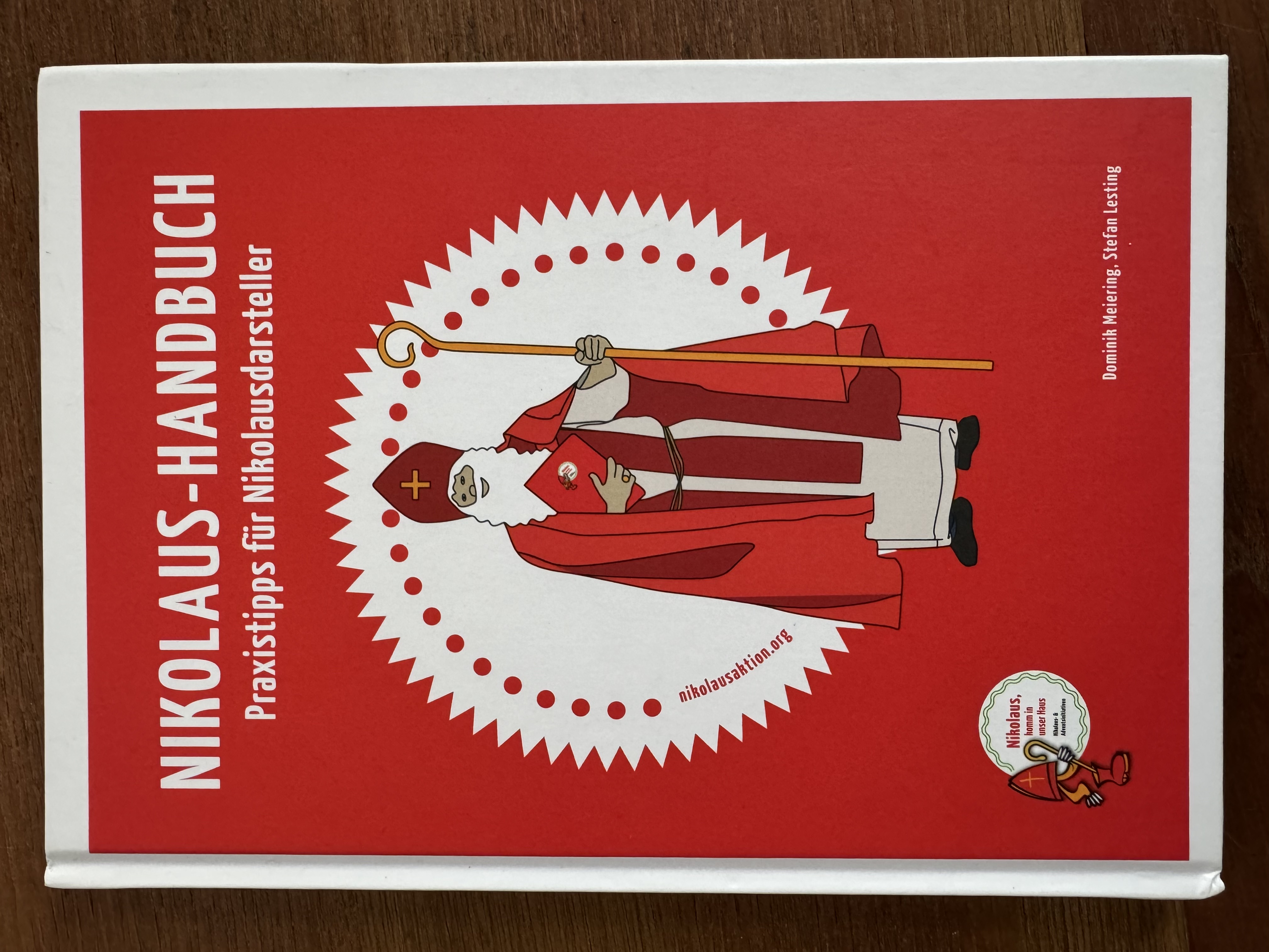 Titelseite des Nikolaus-Handbuch der Bund der Deutschen Katholischen Jugend. Gezeichneter Nikolaus auf einem weißen Kreis mit rotem Hintergrund.